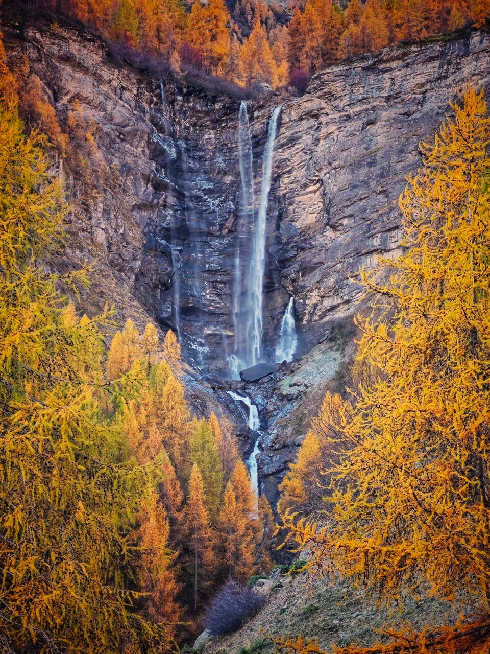 The cascade de la Pisse at Champoléon, among the autumn larches